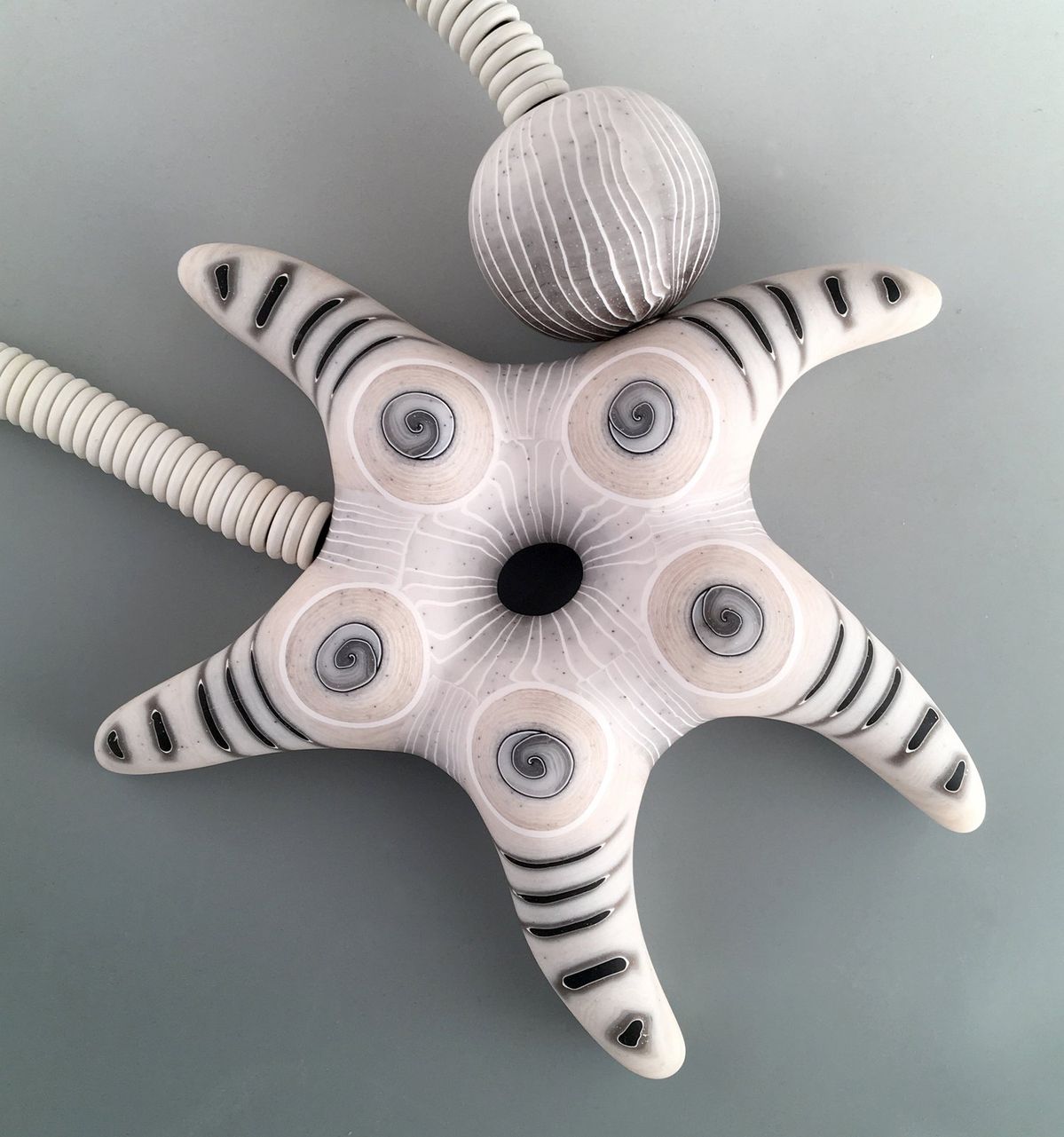 a close-up image of a star-shaped necklace by Melanie West. Features a polymer clay star, ball magnet closure, all in black and white clay.